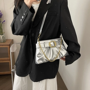 Sac à bandoulière argenté plissé avec boucle dorée et chaîne porté par un modèle