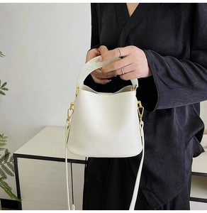 Détail du sac seau blanc avec poignée en résine et finitions dorées sur modèle
