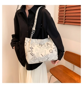 Detail of cream white tote bag with letter prints and chain leather strap on model