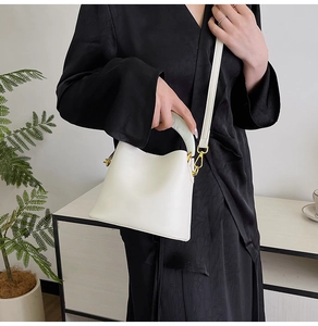 Vue détaillée du sac seau blanc minimaliste avec poignée en résine et finitions dorées
