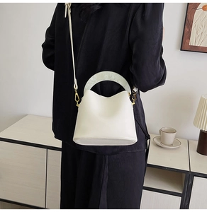 Détail du sac seau blanc avec poignée en résine marbrée verte et finitions dorées