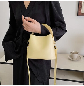 Sac seau beige avec poignée en résine et bandoulière longue porté par un mannequin chic