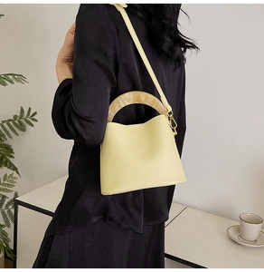 Détail du sac seau crème avec poignées en résine marbrée et bandoulière réglable