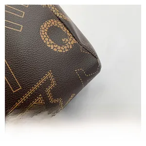 Macro detail of brown tote bag leather with yellow monogram pattern and stitching