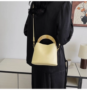 Détail du sac seau jaune clair avec poignée en résine marbrée et détails dorés