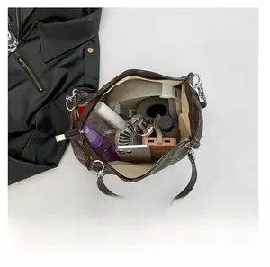 Macro view of the spacious brown tote bag interior filled with daily tech and cosmetics