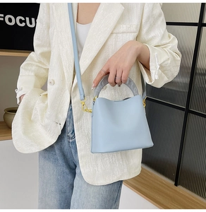 Détail du sac seau bleu clair avec poignée en résine et finitions dorées chic