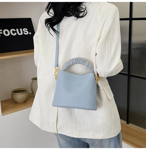 Sac seau bleu clair avec poignée en résine marbrée et bandoulière porté par un mannequin