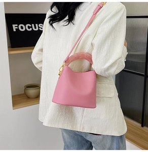 Sac seau rose avec poignée en résine marbrée et bandoulière réglable sur le mannequin