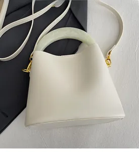Détail du sac seau crème avec poignée en résine marbrée et crochets en métal doré