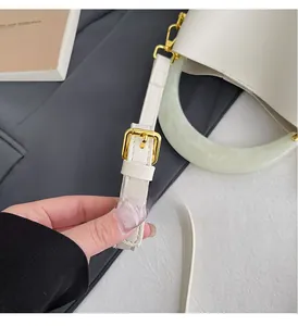 Détail de la poignée en résine marbrée verte et ferrures dorées du sac seau beige