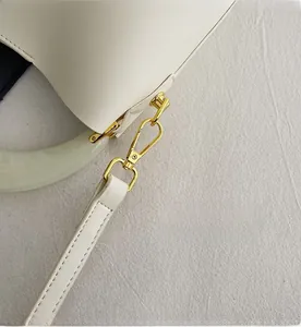 Détail du crochet en métal doré et de l'anse en résine sur le sac seau blanc