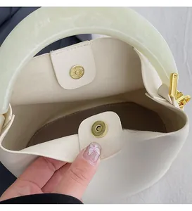 Détail du sac seau crème avec poignée en résine et fermoirs magnétiques dorés