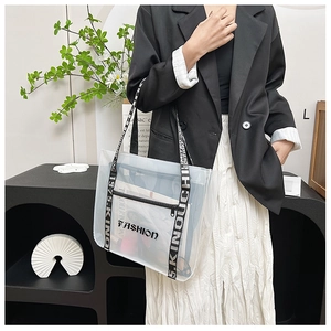 Detail view of transparent PVC tote bag with black FASHION logo and canvas strap