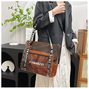 Detail of transparent brown PVC tote bag with wide strap and white fashion text