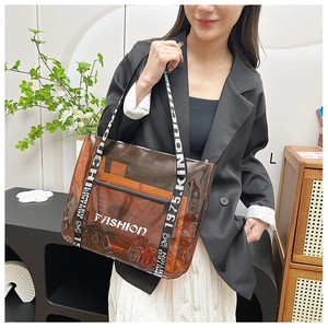 Detail of transparent brown PVC tote bag with FASHION logo and woven shoulder strap
