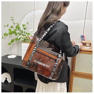Detailed shot of transparent PVC tote with orange inner pouch and lettered fabric strap