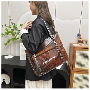 Close-up of brown transparent PVC tote bag with white FASHION text and nylon strap