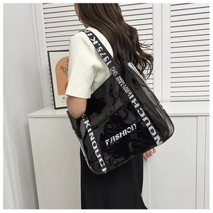Detail of a large black waterproof PVC tote bag with white fashion lettering and strap