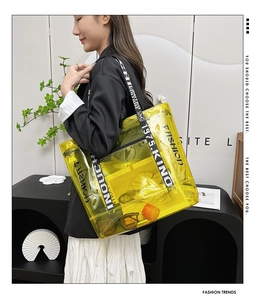 Detail view of yellow transparent PVC tote bag with stylish lettered wide strap