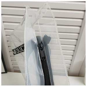 Detail of transparent PVC tote bag with black zipper and TOUCH lettered strap