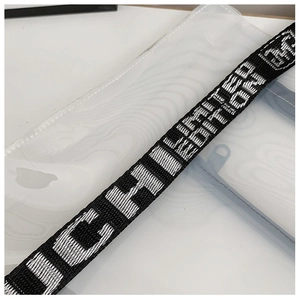 Close-up of black woven shoulder strap with white text on a clear PVC tote bag