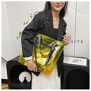 Detailed close-up of a large yellow transparent PVC tote bag with stylish lettered straps