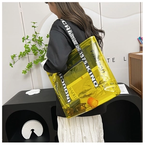 Detail of yellow transparent PVC tote bag featuring bold graphic strap and large interior space