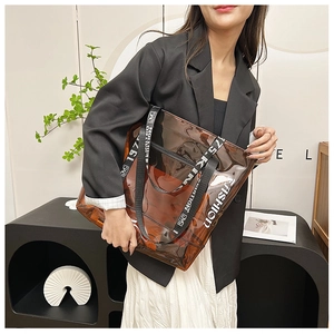 Detail of transparent brown PVC tote bag with FASHION print and woven letter strap