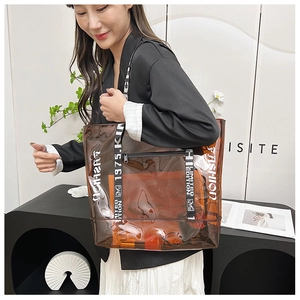Detail of transparent PVC tote bag featuring white fashion typography and black straps
