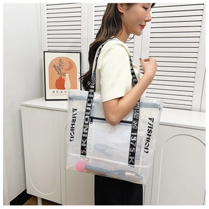 Close-up of clear PVC tote bag featuring black letter printed straps with model on white background