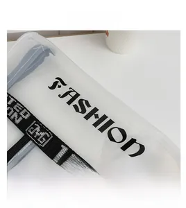 Detail of transparent PVC tote bag with FASHION print and woven handles on white surface