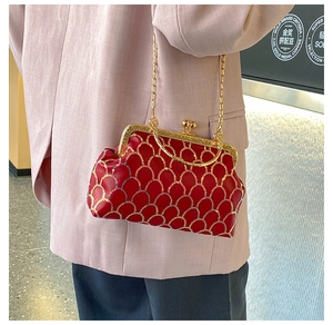 Dettaglio borsa qipao rossa con ricamo a squame dorate e manico rotondo metallico
