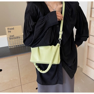 Detail of light green pleated crossbody bag with slim adjustable strap on shoulder