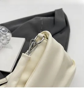 Gros plan sur la texture du cuir plissé blanc crème et la boucle en métal argenté
