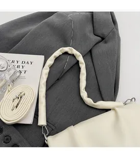 Détail de sac en similicuir crème avec poignée plissée et bandoulière assortie