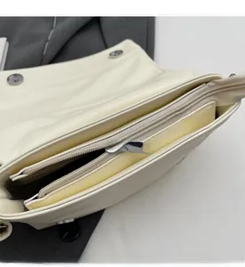 Détail de la fermeture éclair argentée et du compartiment intérieur du sac blanc crème