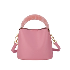 Sac seau rose avec poignée en résine marbrée et bandoulière amovible sur fond blanc
