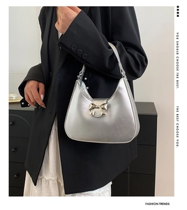 Detail of silver metallic hobo bag with bow buckle decoration on a model shoulder