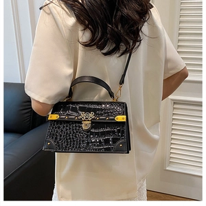 Modella con borsa nera a motivo coccodrillo ed elegante chiusura in metallo dorato