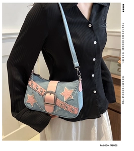 Detail of Y2K denim shoulder bag featuring pink star appliqué and silver metal chain strap