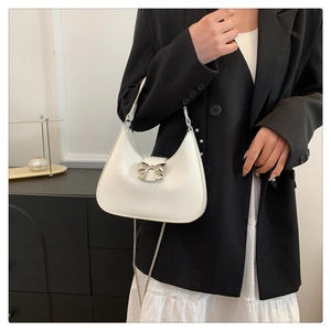 Detailed side view of white leather hobo bag with silver bow buckle and chain strap