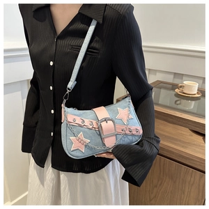 Detail of blue denim Y2K shoulder bag with pink stars, metal eyelets and silver chains