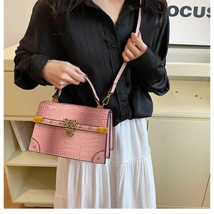Dettaglio borsa rosa effetto coccodrillo con finiture dorate e decoro a cuore