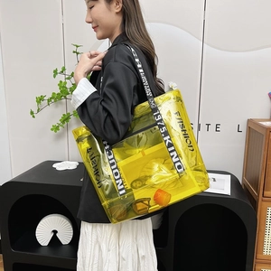 Transparent yellow PVC tote bag with black and white letter print shoulder strap in use