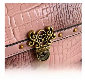 Dettaglio borsa rosa con trama a coccodrillo e chiusura a cuore dorata vintage