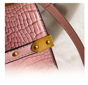 Dettaglio pelle di coccodrillo rosa con rivetti dorati vintage e fibbie metalliche