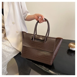 Macro detail of the dark brown crocodile embossed leather texture on a tote handbag
