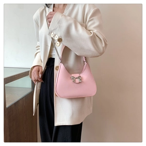 Close-up of pink crescent underarm bag with silver bow buckle and chain detail