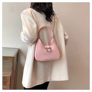 Dettaglio borsa a spalla in pelle PU rosa con fibbia a fiocco e tracolla a catena in metallo
